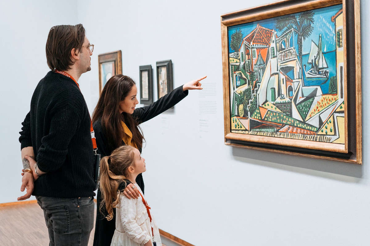 A family stands in front of the painting “Mediterranean Landscape” in an exhibition, the mother points to the painting | Photo © Marko Mestrovic