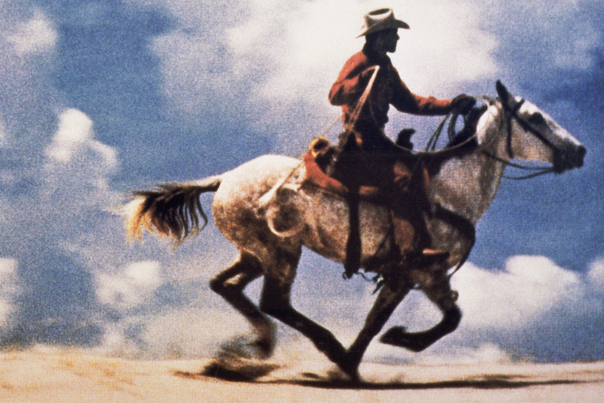 Farbfotografie eines Cowboys auf einem galoppierenden Pferd in weiter Landschaft; großformatiger, horizontaler Bildausschnitt. Credit: Richard Prince | Untitled (Cowboy), 1989 | Courtesy of Richard Prince Studio © Richard Prince