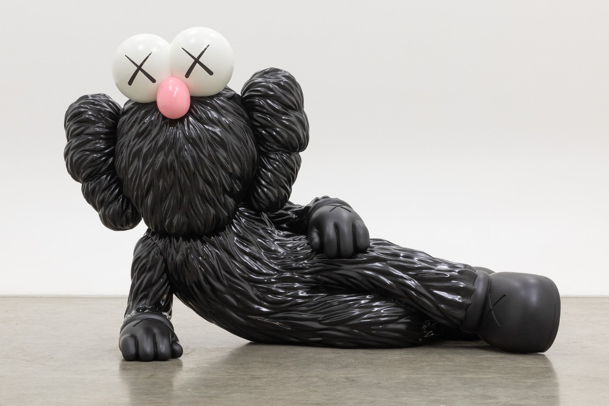 Sculpture of a comic character lying on its side, supported on one side, with black fur, a pink snub nose, and X-shaped eyes.