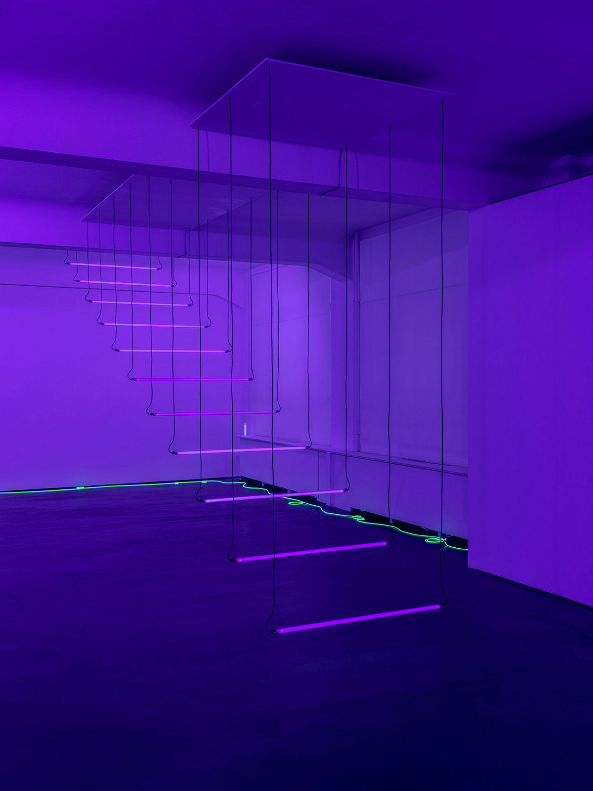 In a purple-lit room, individual steps of purple fluorescent tubes hang down from the ceiling like a flying staircase.