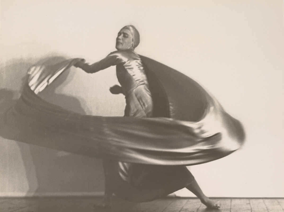 Photograph of a dancing woman in loose, flowing garments in an expressive pose.
