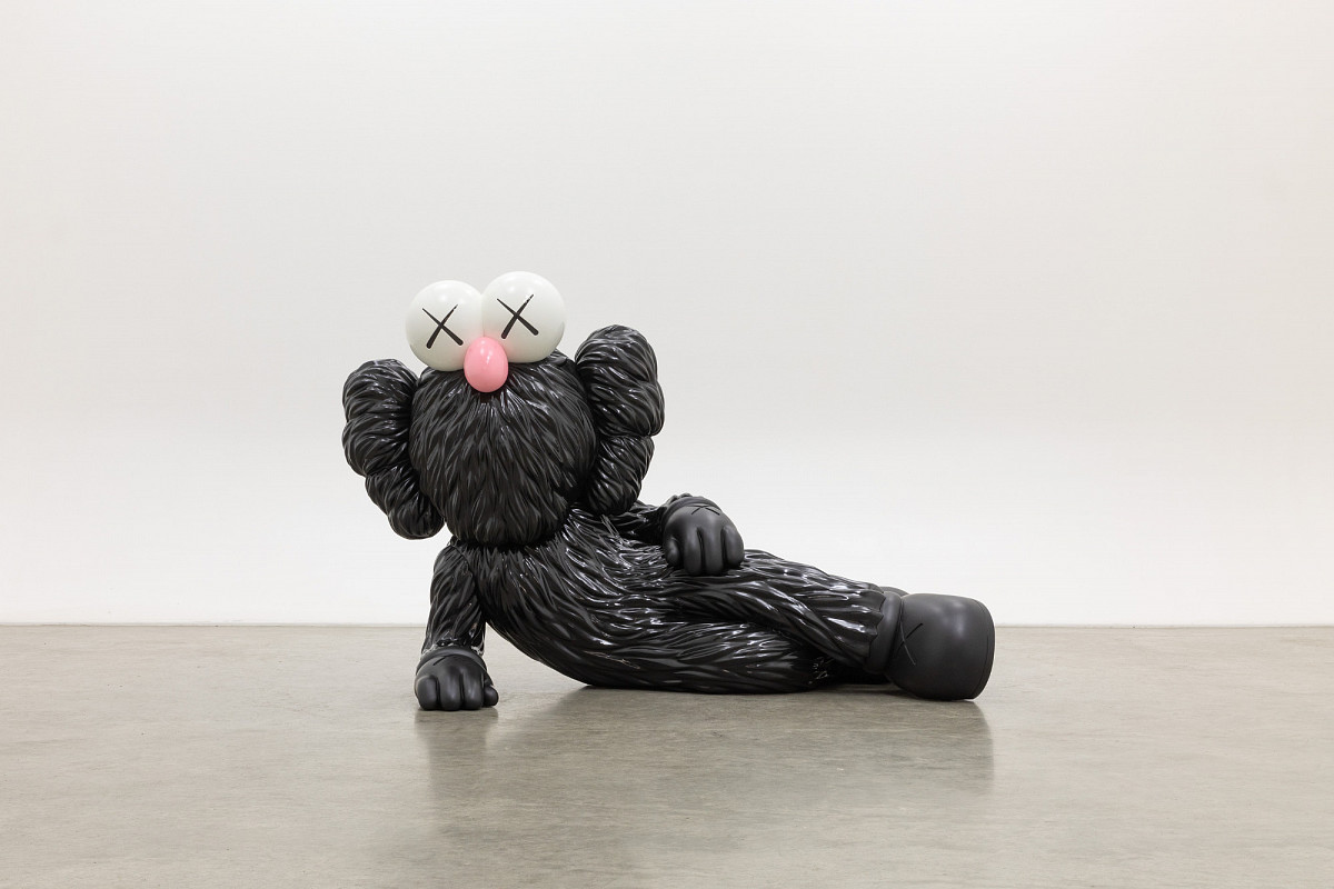 Sculpture of a comic character lying on its side, supported on one side, with black fur, a pink snub nose, and X-shaped eyes.