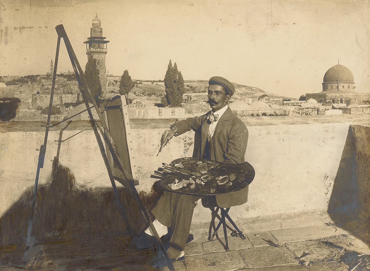 Self-portrait of a man on a terrace overlooking rooftops and buildings in the background.