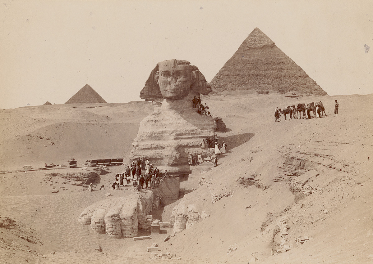 Photograph of the Sphinx with the Pyramids of Giza in the background.