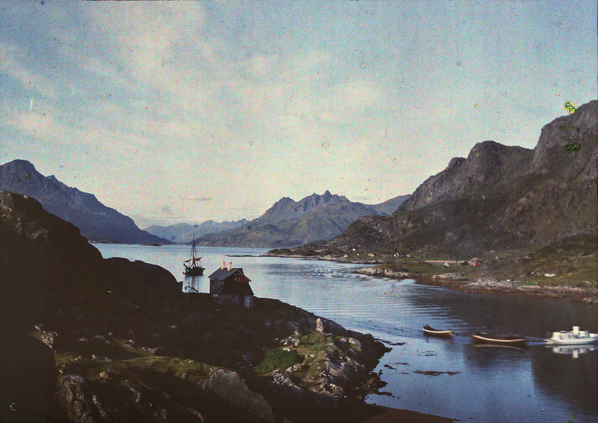 A fjord landscape with mountains, water, and a few houses along the shore.